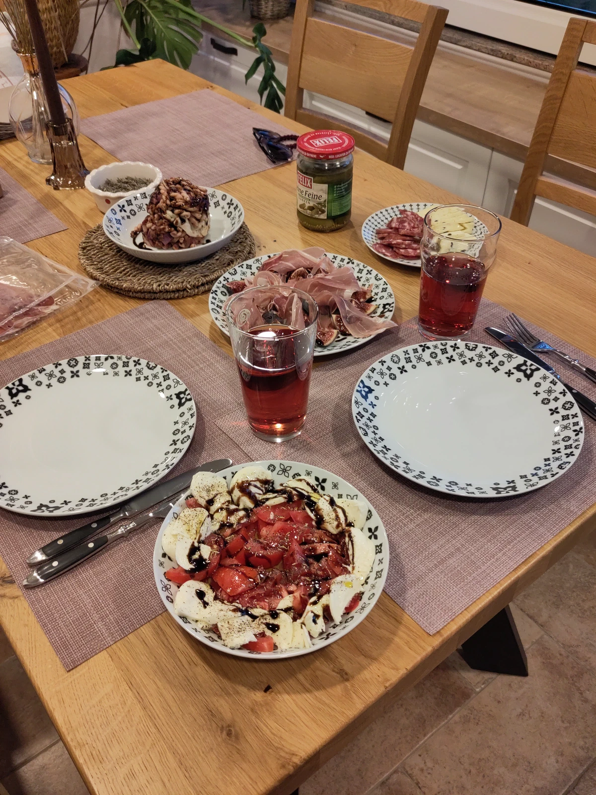 Gedeckter Tisch mit Tomatensalat, Schinken und Rotwein