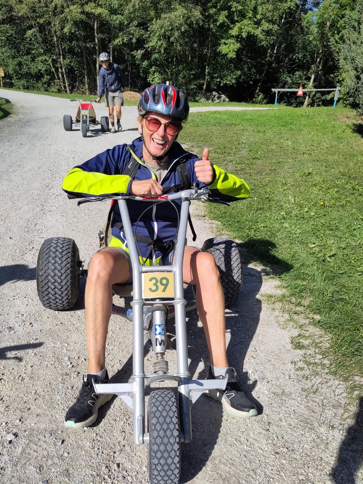 Eine Person mit Helm sitzt im Mountain-Kart und zeigt den Daumen nach oben